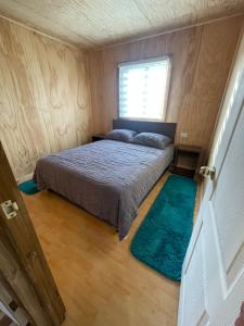 un dormitorio con una cama y una ventana en Cabañas de campo, en Angol