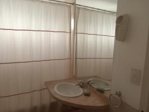 Un baño blanco con lavabo y espejo. en Oro Plaza Apartamentos, en Buenos Aires 26 fotos más