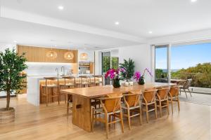 a kitchen and dining room with a large wooden table and chairs at Bombora Beach House in Noosa in Marcus Beach