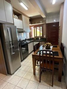 eine Küche mit Tisch und Edelstahlkühlschrank in der Unterkunft Casa de veraneio 2 dormitórios in Torres