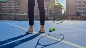 una persona che tiene in mano una racchetta da tennis e due palline su un campo da tennis di Sonoran Spa W403 a Campo del Medio