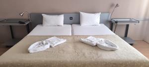 two pairs of white shoes sitting on a bed at ATM Hotel in Sofia +1 photo