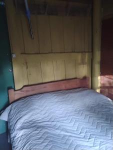 a bed with a wooden headboard in a room at Cabaña in Punta Del Diablo