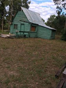 a green building with a metal roof in a field at Cabaña in Punta Del Diablo