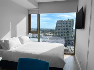 une chambre avec un lit blanc et une grande fenêtre dans l'établissement The Cullinan Apartments by CLLIX, à Adélaïde