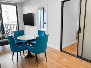 une salle à manger avec une table et des chaises bleues dans l'établissement The Cullinan Apartments by CLLIX, à Adélaïde