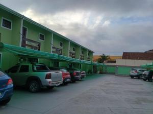 a green building with cars parked in a parking lot at Casa Caraguá in Caraguatatuba