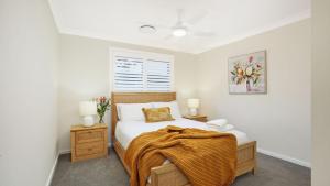 a bedroom with a bed with a blanket on it at Coastal Drift in Callala Bay +28 photos