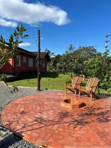 two wooden benches sitting on a brick patio at Morada dos Pomares in Pomerode