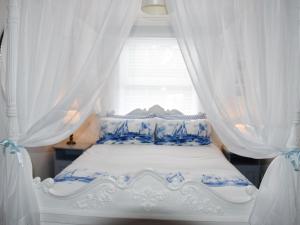 a white bed with blue and white curtains at Buzzards - 8235 in Bridport +7 photos
