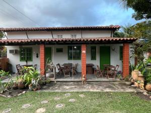 une petite maison blanche avec une table et des chaises dans l'établissement Pousada Canto da Reg, à Santa Cruz Cabrália