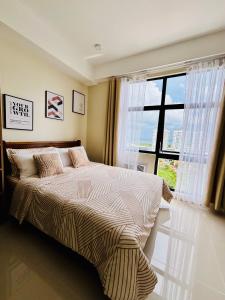 a bedroom with a bed with a large window at The Asher Mactan in Mactan