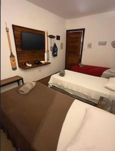 um quarto de hotel com duas camas e uma TV de tela plana em Cabana da Mari em Fernando de Noronha