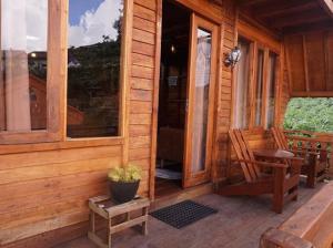 une cabane en bois avec un banc et une chaise sur un porche dans l'établissement Danial Cabin Dieng, à Diyeng
