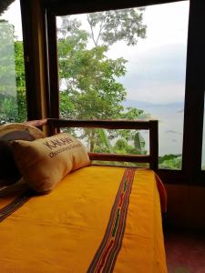 a bed with a pillow in front of a window at Ecolodge Rancho del Lago in Santomé