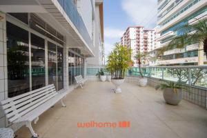 uma passarela com bancos e vasos de plantas em um prédio em Apartamento em Praia Grande a 600 metros do mar na Praia Grande