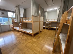 a dorm room with bunk beds and a wooden floor at 三陸アクティブ in Ōfunato