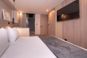 a bedroom with a white bed and a flat screen tv at Jatisa Living by Housy in Medellín