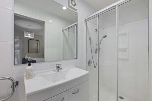 a white bathroom with a sink and a shower at Marina Edge Marlborough Sounds Apartment in Waikawa