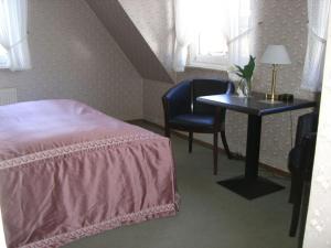 een slaapkamer met een bed, een tafel en een stoel bij Haus Roswita in Bad Harzburg