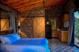 リオネグロにあるRomantic Glamping Cabin with Jacuzzi & Viewsのベッドとレンガの壁がある寝室