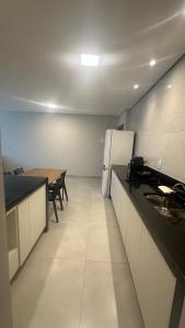 a kitchen with a table and a white refrigerator at Apê da Bella seu refúgio no Caparaó in Alto Caparao