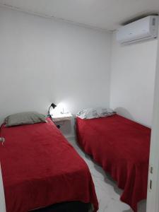 two beds in a room with red sheets at alojamiento lolita in Puerto Iguazú