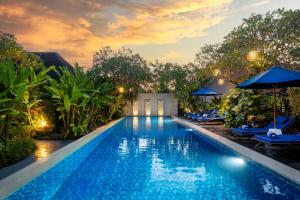 a pool with chairs and umbrellas at a resort at Rama Residence Seminyak in Seminyak