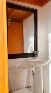 a bathroom with a sink and a toilet and a mirror at Refugio Campestre, Cabaña con Tinaja Opcional  +17 photos