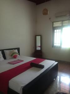 a bedroom with a large bed with a red and white blanket at Tiny Villa Homestay - ONLY FOR FOREIGN BOOKINGS in Kurunegala