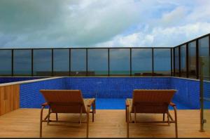 two chairs and a table on top of a balcony at Flat luxo Tambaú in João Pessoa