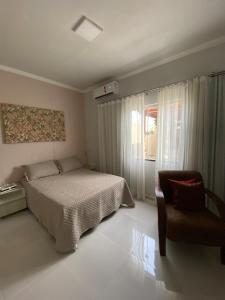 una camera da letto con un letto, una sedia e una finestra di Casa a 2 minutos da praia a Prado