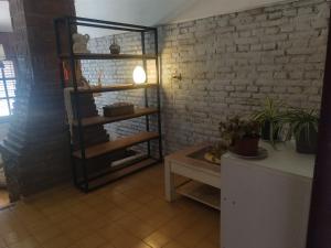 ein Raum mit einem Regal und einem Tisch und einer Ziegelwand in der Unterkunft Casa Grande con pileta próximo kempes, ferial, Córdoba in Cordoba