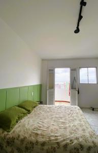 a bedroom with a large bed with a green headboard at Quarto suíte para COP30 in Belém