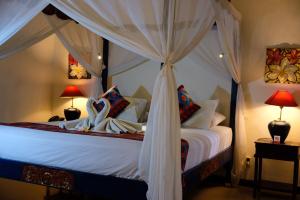 a bedroom with a canopy bed with white sheets and pillows at Puri Cendana Resort Bali in Seminyak +47 photos
