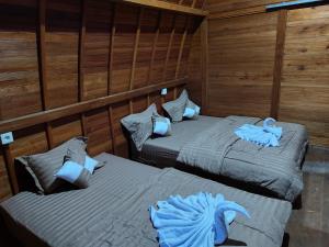 two beds in a room with wooden walls at Batur Water Park Cabin in Kubupenlokan