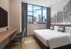 a hotel room with a bed and a desk and a window at Days Inn by Wyndham Zhuhai Qinglv Road in Zhuhai
