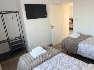 a room with two beds and a flat screen tv at Athlon Apartment in Río Gallegos