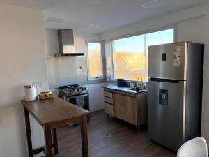 a kitchen with a stainless steel refrigerator and a wooden table at Athlon Apartment in Río Gallegos