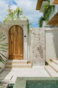 a wooden door of a house with stairs and a pool at Sawah Villas Pantai Lima in Pererenan