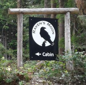 a black sign with a black bird on it at Little Bear Cabin at Raven's Moon in Ucluelet