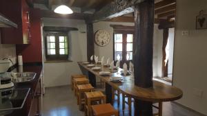 a long table in a kitchen with a clock on the wall at Camino de la Torre in Quintana de Soba