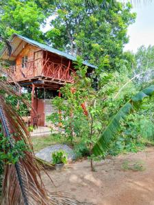 a wooden house with a balcony in the woods at Farming Tree House in Sigiriya