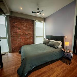a bedroom with a bed and a brick wall at Brick Box Loft con Balcon in Hércules