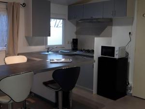 a kitchen with a counter and two bar stools at Mobil-home confortable avec terrasse à Sournia - API-1-52-358 in Sournia