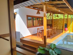 a villa with a pool and a wooden deck with a table at Villa Santai Mentawai in Tua Pejat