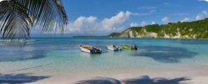 three boats sitting in the water on a beach at La BEL KREOL in Le Gosier