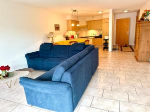 a living room with a blue couch and a kitchen at Haus Alpina - CharmingStay in Flumserberg