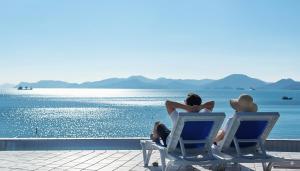 two people sitting in chairs looking at the water at Namhae Pumda Pool villa Pension in Namhae