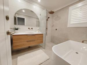 ein Badezimmer mit Waschbecken, Badewanne und Spiegel in der Unterkunft Charming Coastal Cottage Retreat in Vincentia + 13 Fotos